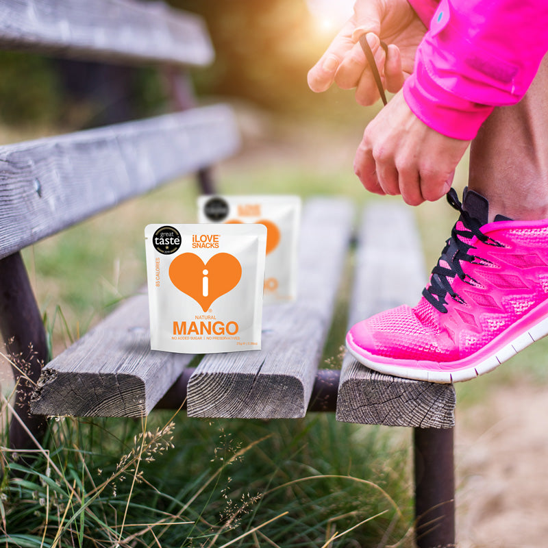 iLOVE Snacks gently dehydrated mango, pictured on a park bench with a runner in pink running gear